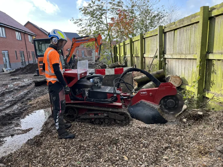 Landywood operator using a stump grinder beside timber fencing